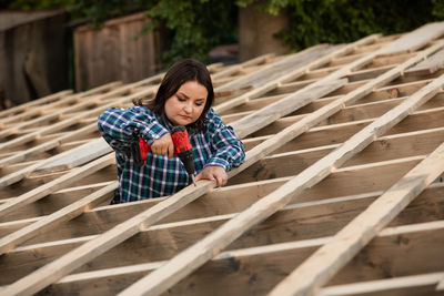 Young woman looking away while standing on wood