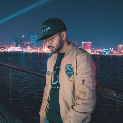 Man standing in illuminated city against sky at night