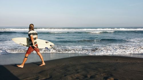 Woman standing on beach against clear sky