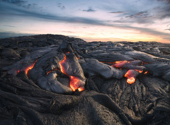 Bonfire on rock against sky during sunset