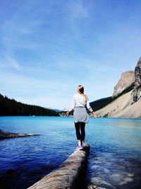 Full length of young woman standing on lake against sky