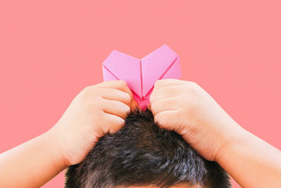 Rear view of man holding paper against pink background