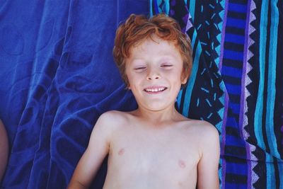 High angle view of smiling shirtless boy lying at home