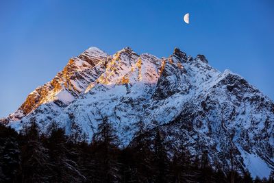 Low angle view of snowcapped mountains against clear blue sky at night