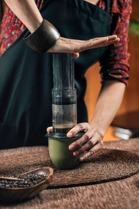 Midsection of woman making coffee in cafe