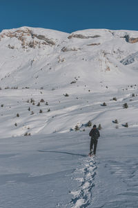 An unrecognizable male hiker wearing snowshoes walking in the french alps