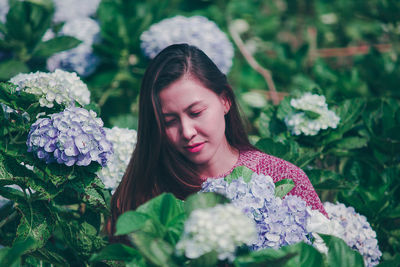 Close-up of woman with pink flowers against blurred background