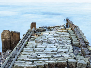 Stone wall by sea against sky