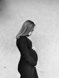 Side view of pregnant woman against wall