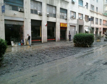 Wet street by buildings in city