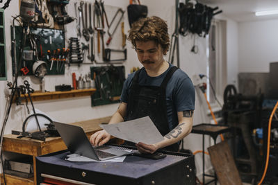 Blacksmith using laptop in workshop