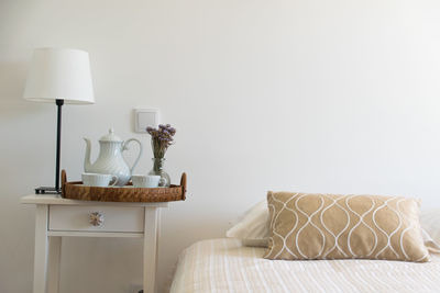 Electric lamp by teapot and cups in bedroom