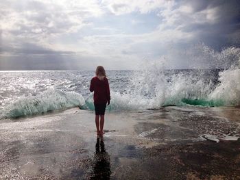 Woman standing on sea shore against sky