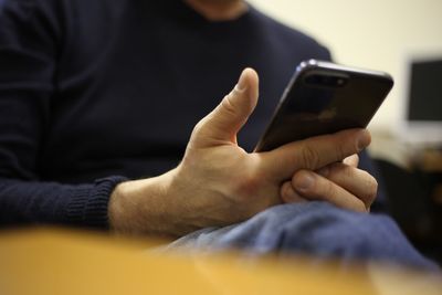 Midsection of man using mobile phone at home