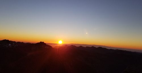 Scenic view of silhouette mountains against clear sky during sunset