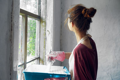 Rear view of woman standing against window