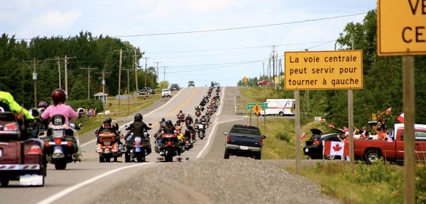 Rear view of riders on road against sky