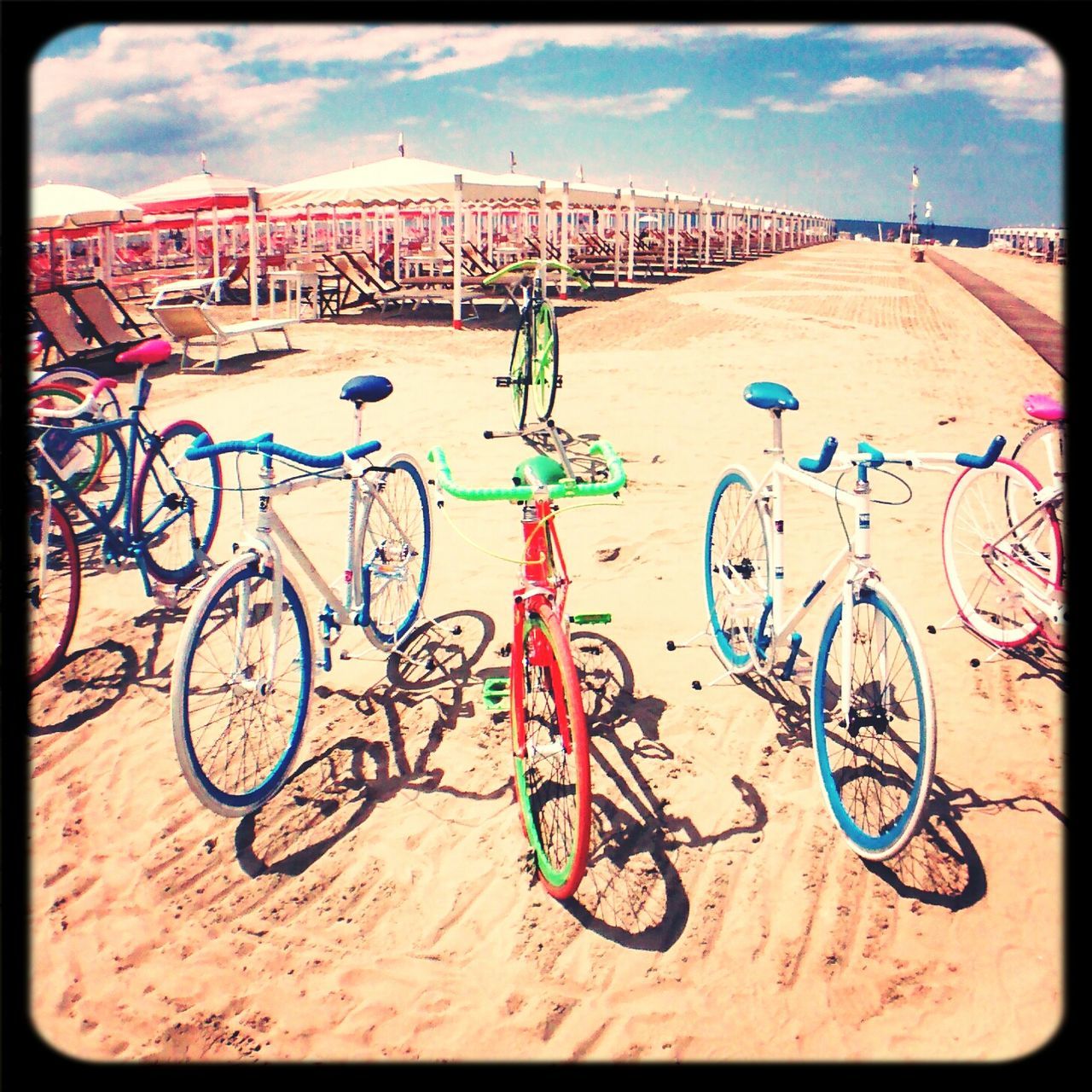 transfer print, auto post production filter, bicycle, transportation, sky, graffiti, land vehicle, day, mode of transport, street, sunlight, outdoors, stationary, creativity, parking, art and craft, built structure, sand, shadow, cloud - sky