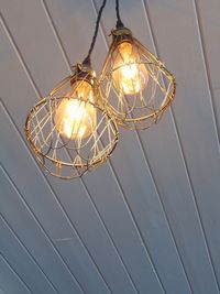 Low angle view of illuminated light bulb hanging from ceiling