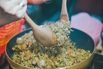 Midsection of person preparing food in cooking pan