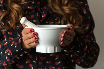 Midsection of woman holding white mortar and pestle