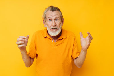 Portrait of young woman gesturing against yellow background