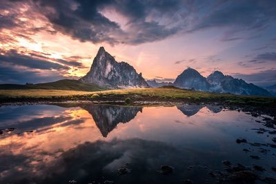 Scenic view of lake by mountains against sky during sunset