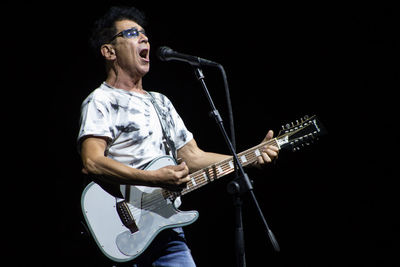 Man playing guitar against black background