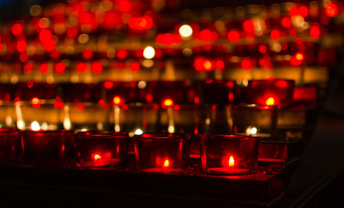 Illuminated burning tea lights at church in dark