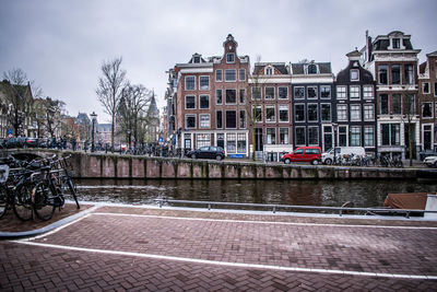 Buildings by river against sky in city