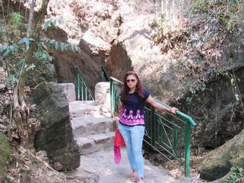 Portrait of smiling young woman standing against trees