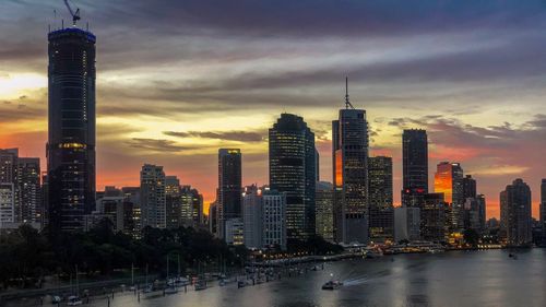 Illuminated buildings in city against sky during sunset