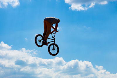 Low angle view of man with bicycle against sky