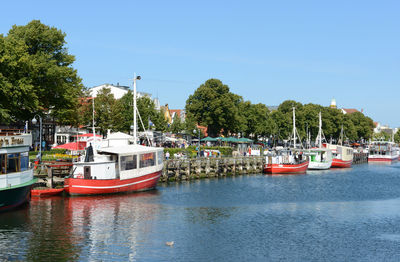 Fishing boats moored in canal against sky