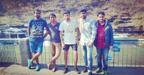 Full length portrait of friends standing by swimming pool