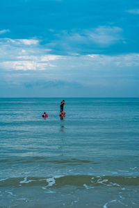 Father and kids enjoying at sea against sky