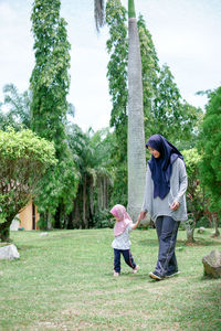Rear view of friends standing by trees against plants