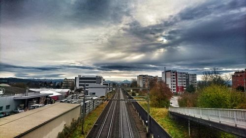 View of railroad tracks in city against cloudy sky