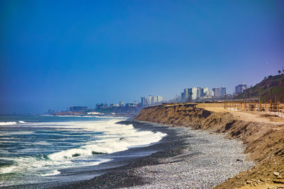 Scenic view of beach against clear blue sky