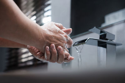 Cropped image of person washing hands at home
