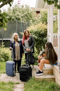 Multi-generation family with luggage standing outside house