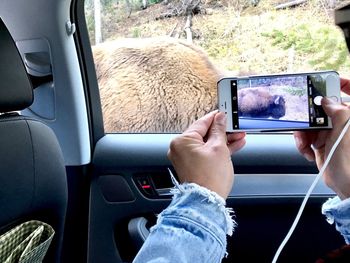 Midsection of man using mobile phone in bus