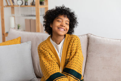 Portrait of young woman sitting on sofa at home