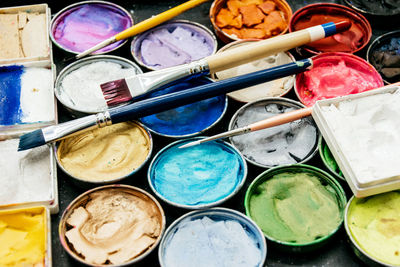 Multicolored watercolor paints and brushes for painting