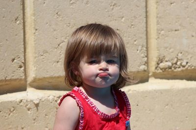 Portrait of cute girl standing against wall