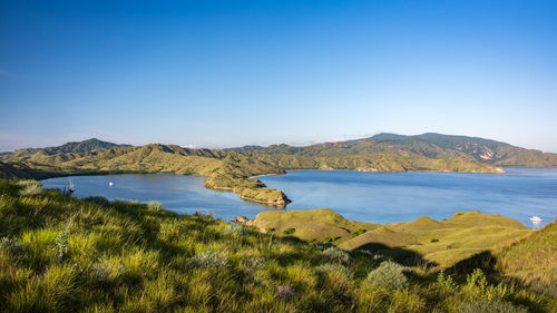 Scenic view of lake and mountains against clear blue sky