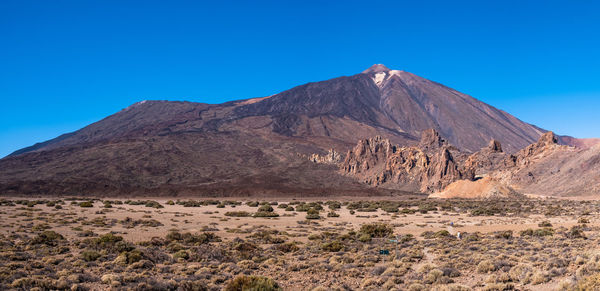 Scenic view of mountains against clear blue sky