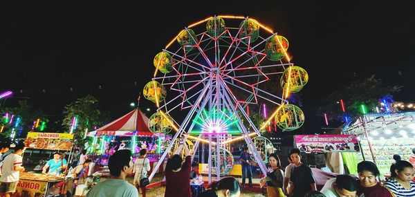 Illuminated ferris wheel against sky at night