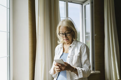 Woman with eyeglasses using mobile phone at home