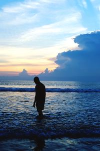 Man standing on beach against sky during sunset